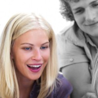 Young guys and girls sitting on floor holding white paper looking on it smiling